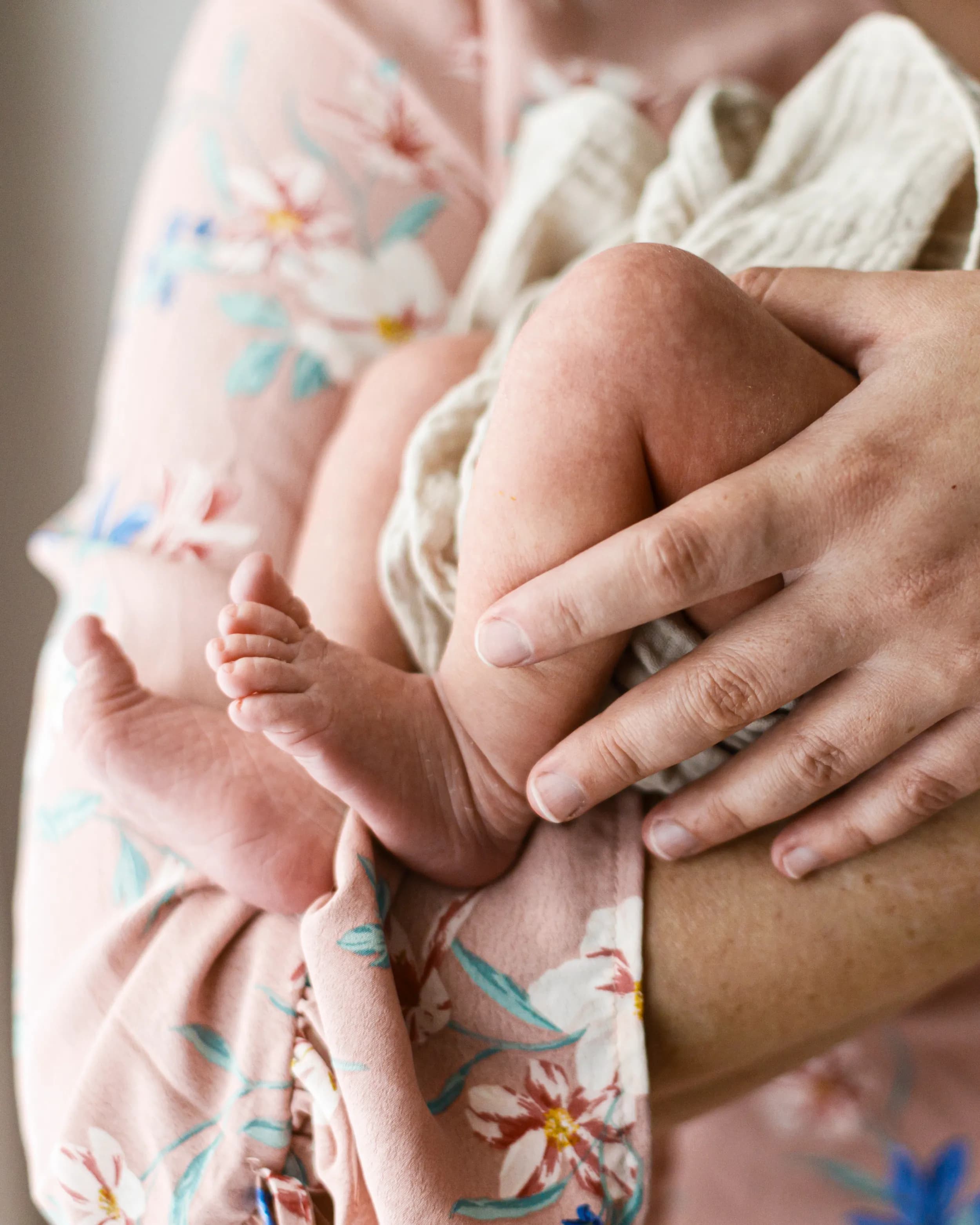 Supportive hands gently holding a newborn baby at home.